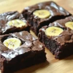 Moist chocolate and banana brownies on a wooden tray