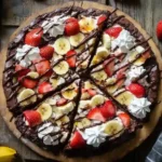 Fully assembled banana brownie pizza with fresh fruit and syrup