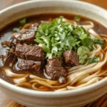 Bowl of beef and noodles with beef broth and parsley